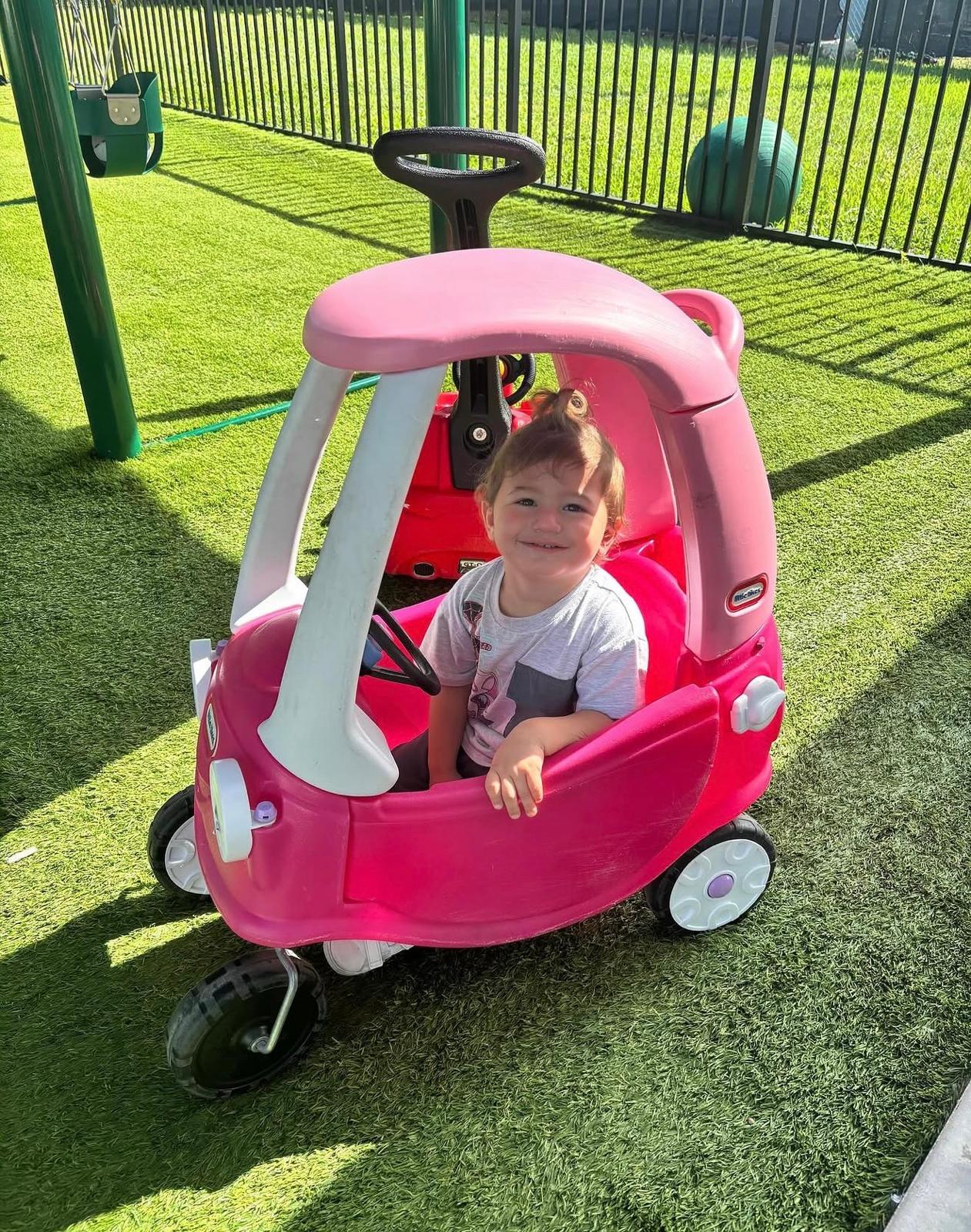 A toddler in a ride-on car on the playground